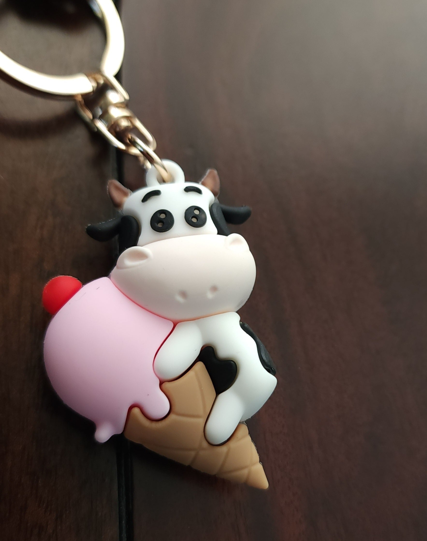 Keychain with a cow on an ice cream cone against a wooden background